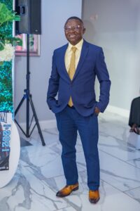 Man in a sharp blue suit poses confidently indoors.